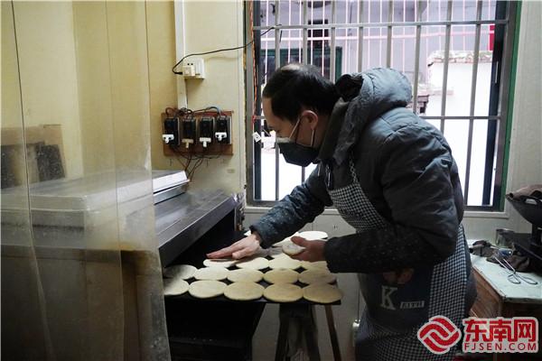 梅梁華從電烤箱中放入燒餅.jpg