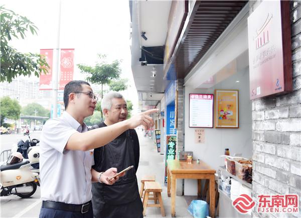 薛建寧（左一）向小吃業(yè)主介紹小吃一卡通使用.jpg